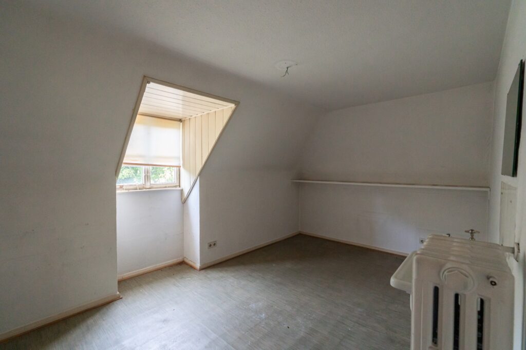 Zimmer im Dachgeschoss mit Dachschräge und Fenster