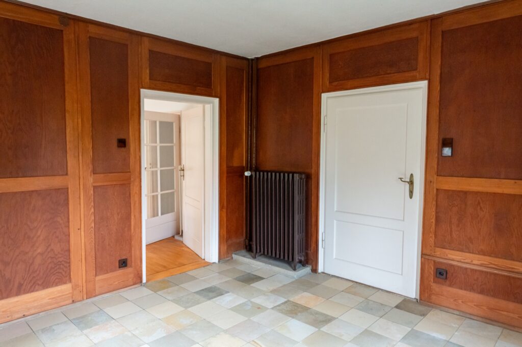 Zimmer mit Holzvertäfelung und Zugang ins Freie