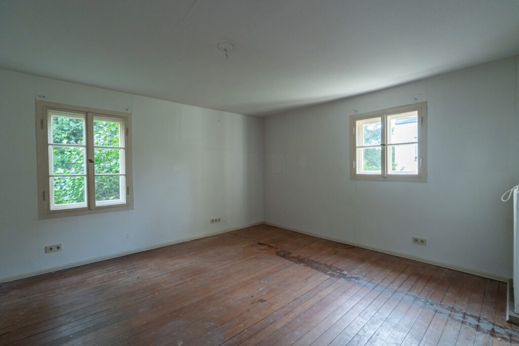 Weiteres Zimmer mit Holzboden und zwei Fenstern