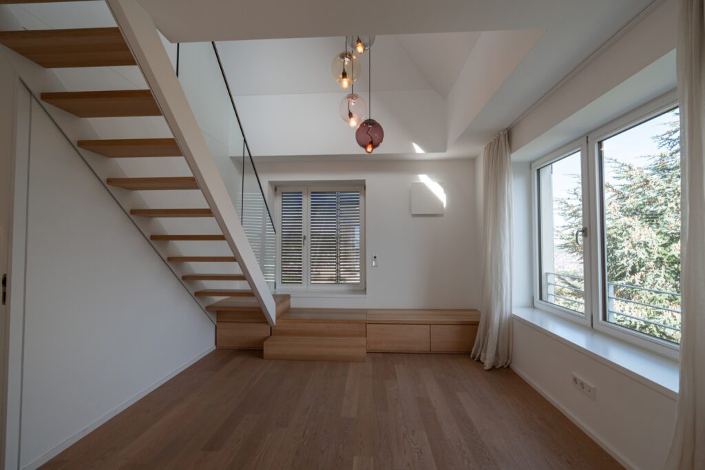 Offener Bereich mit Holztreppe und großem Fenster